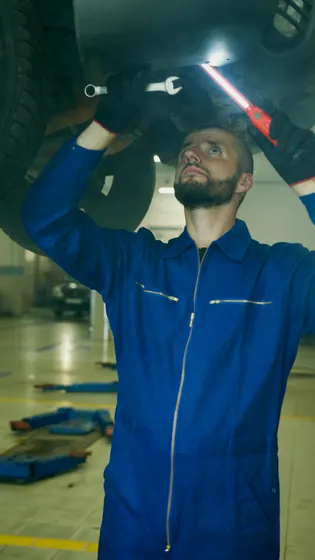Mechanic inspecting underside of vehicle